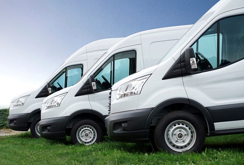 White vans in a row against blue sky