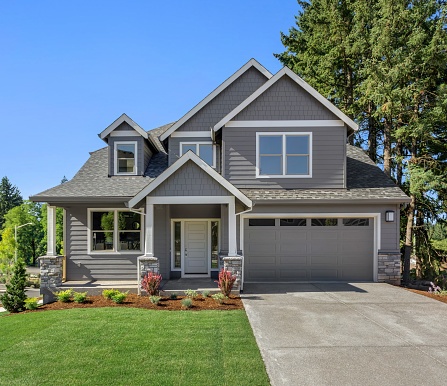 Beautiful residential home exterior on bright sunny day with green grass and blue sky